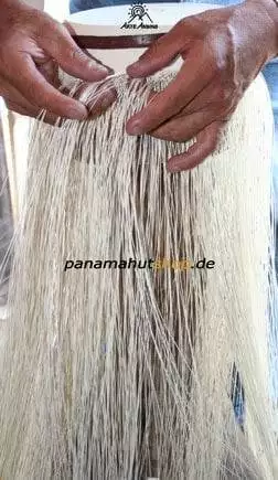 A person makes a hat from a long strand of hair.